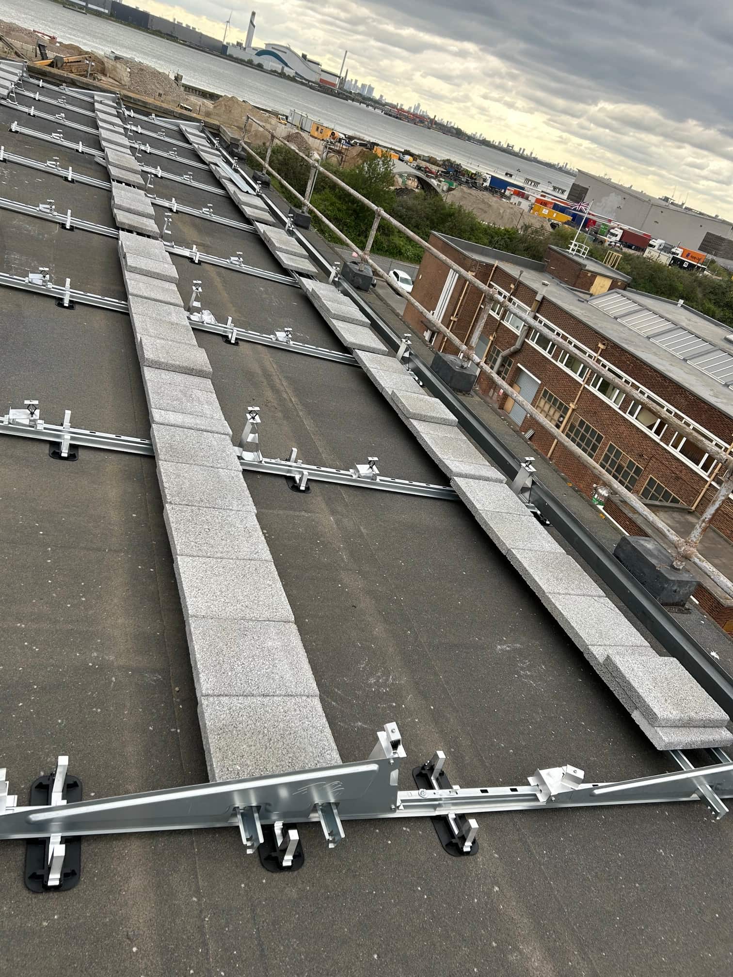 Ballast blocks and galvanised mounting rails laid on a flat roof before solar panel installation in Rainham