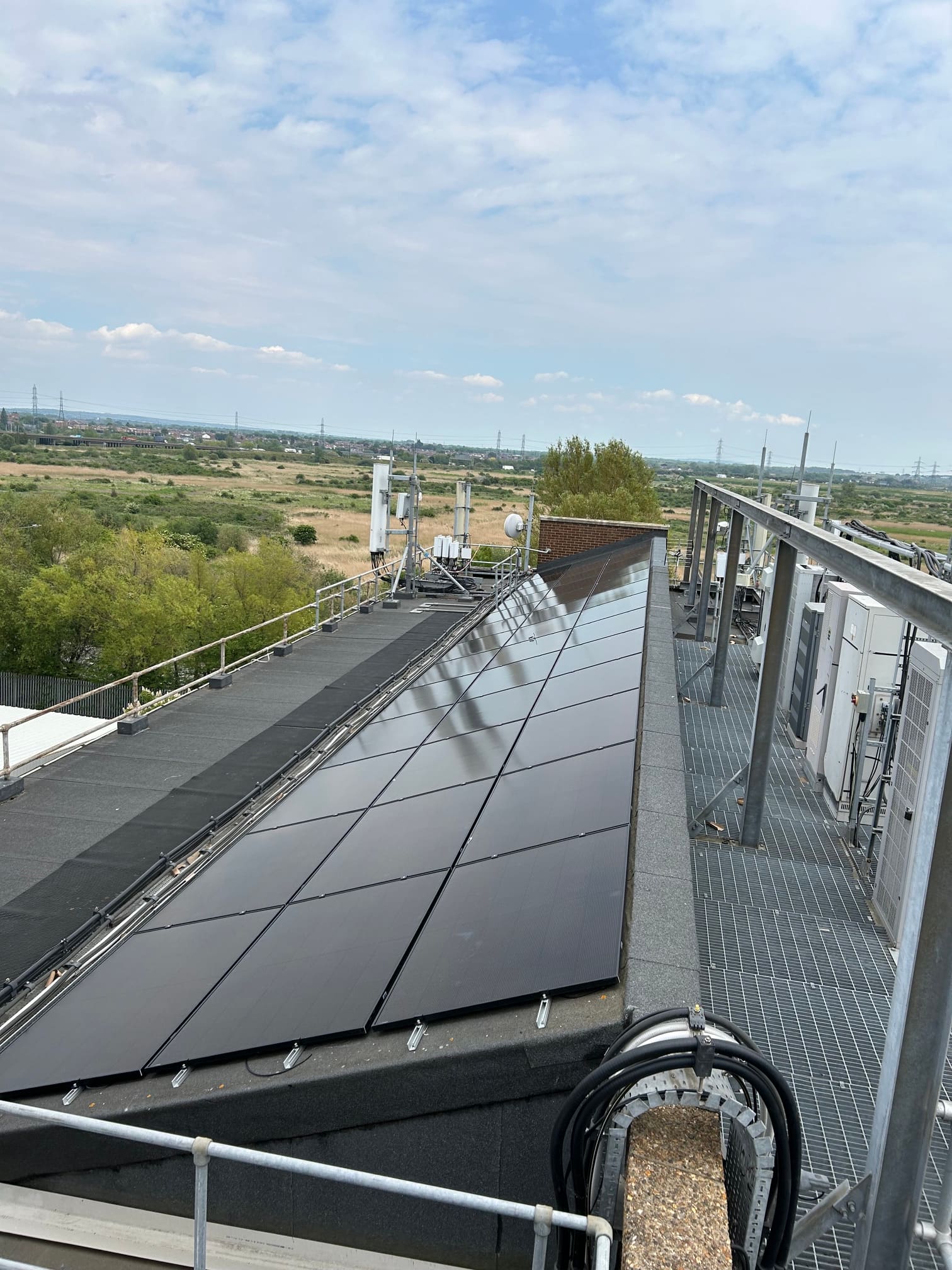 Rooftop solar array alongside the walkway grating, cable tray and air-conditioning plant deck