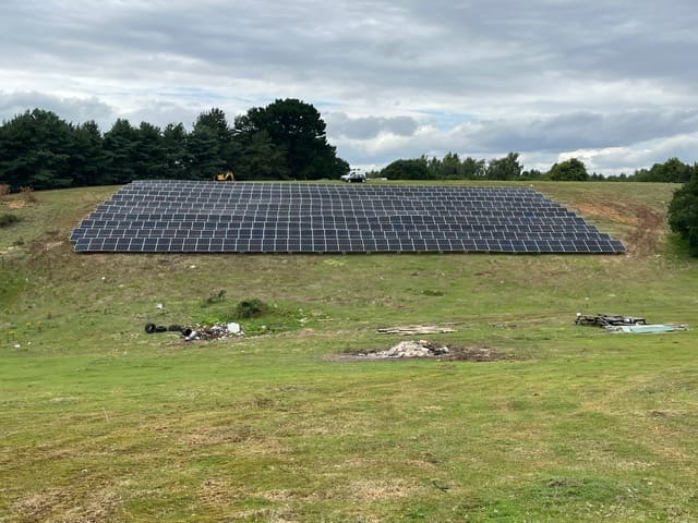 Completed 300kWp ground-mounted solar array on a grass bank at Seckford Hall, screened by mature trees