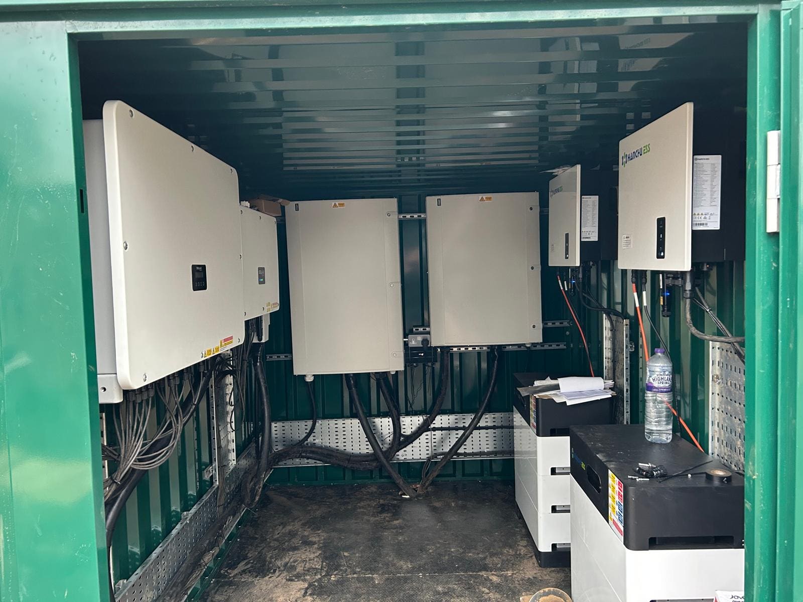 Inverters and battery storage units mounted inside the green plant container at Woodhall Manor